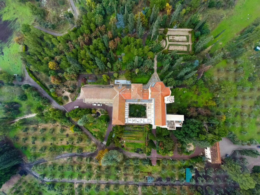 Drone view of a historic monastery surrounded by lush greenery in Jerusalem, Israel.